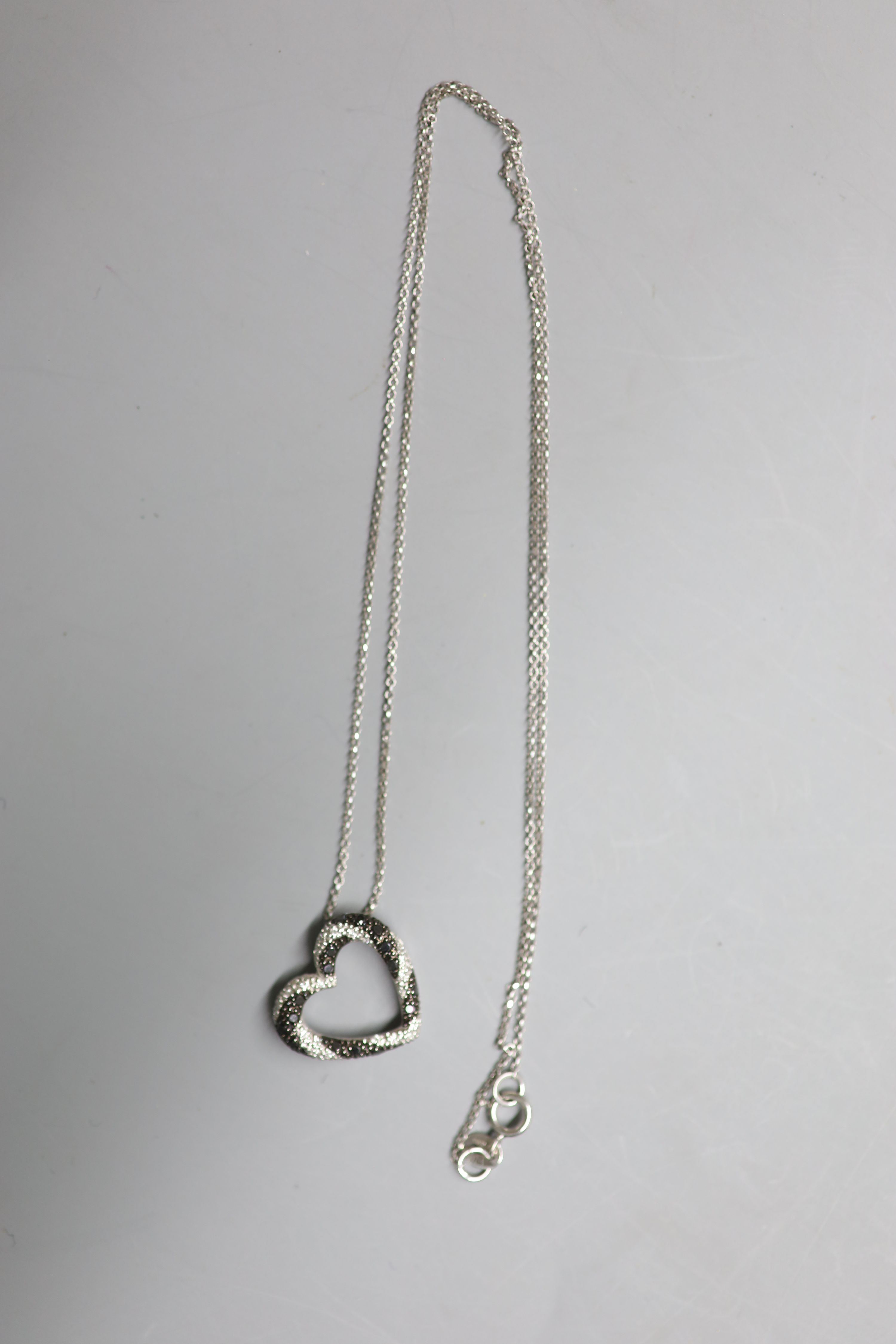 A modern 18ct gold and two colour diamond chip set openwork heart pendant, 16mm, on an 18ct gold fine link chain